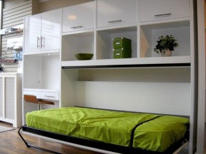 glossy-white-side-tilt-murphy-bed-with-green-bed-cover-and-white-cabinets-and-shelves-610x457